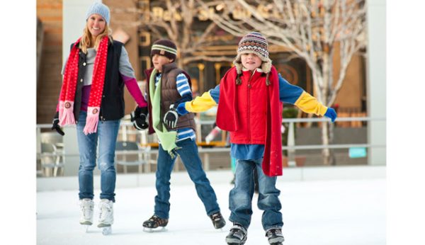 a family skates together at an ice rink