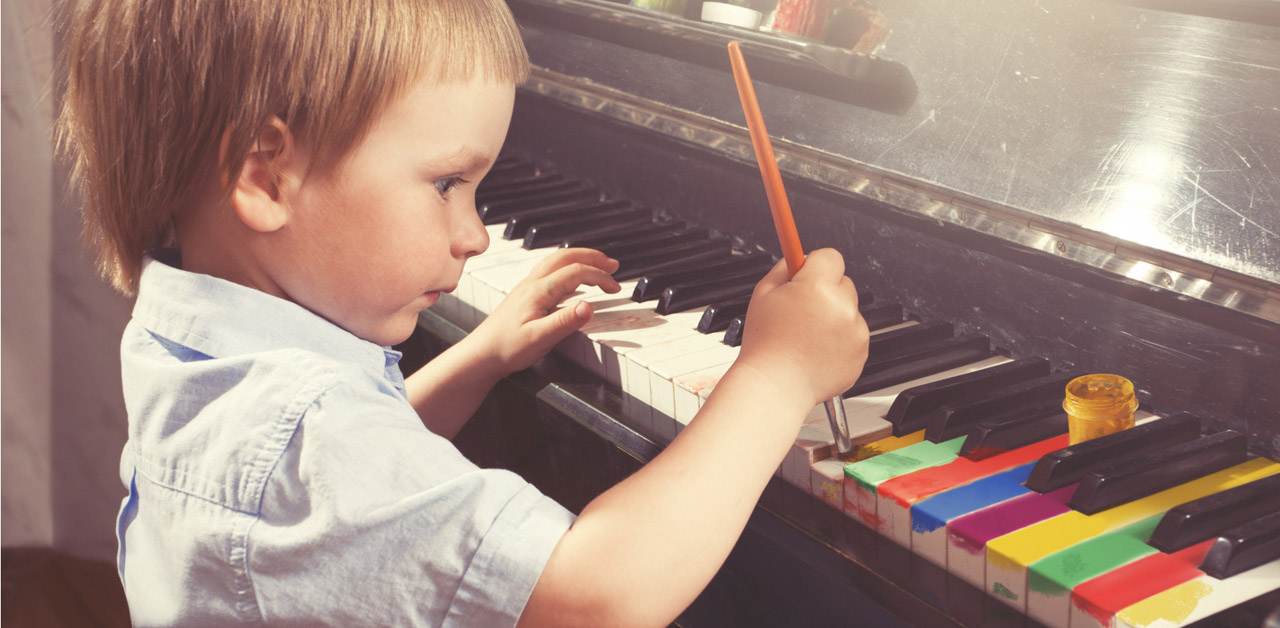 Young boy painting piano keys with brush.