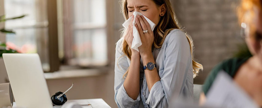 young-sick-businesswoman-sneezing-tissue-while-working-office_637285-1991
