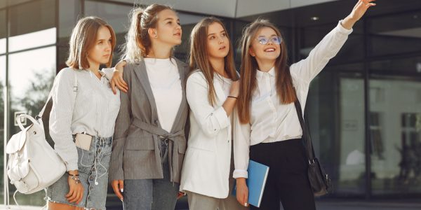 Students in a park. Girls lying on a grass. Friends with a notebooks.